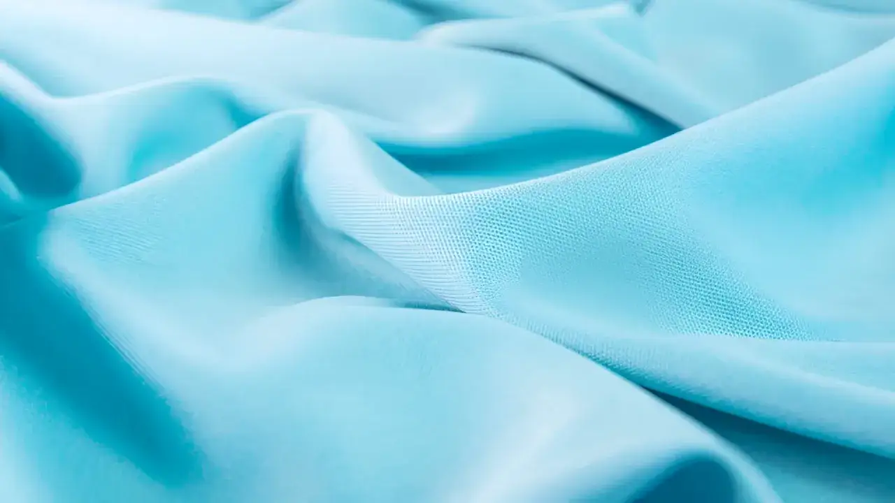 Soft, flowing turquoise fabric. This material, likely lyocell, shows minimal creasing, suggesting it does lyocell wrinkle very little.